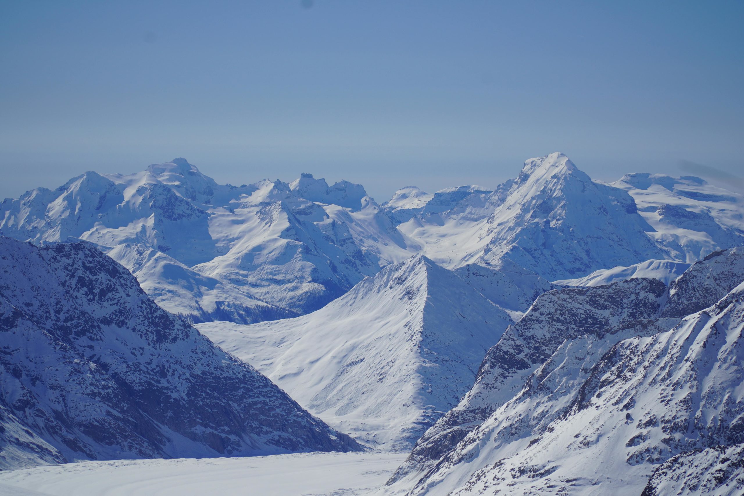 Breathtaking view of snow-covered Alpine mountains under a clear blue sky.