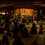 People meditate together inside a dimly lit hall.
