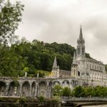 Stunning view of the Basilica of Our Lady of Lourdes against lush green landscape.