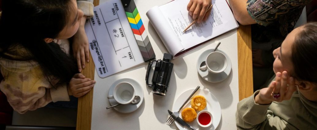 Aerial view of a team discussing a project with a clapperboard in a café setting.