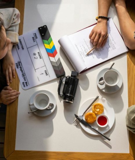 Aerial view of a team discussing a project with a clapperboard in a café setting.